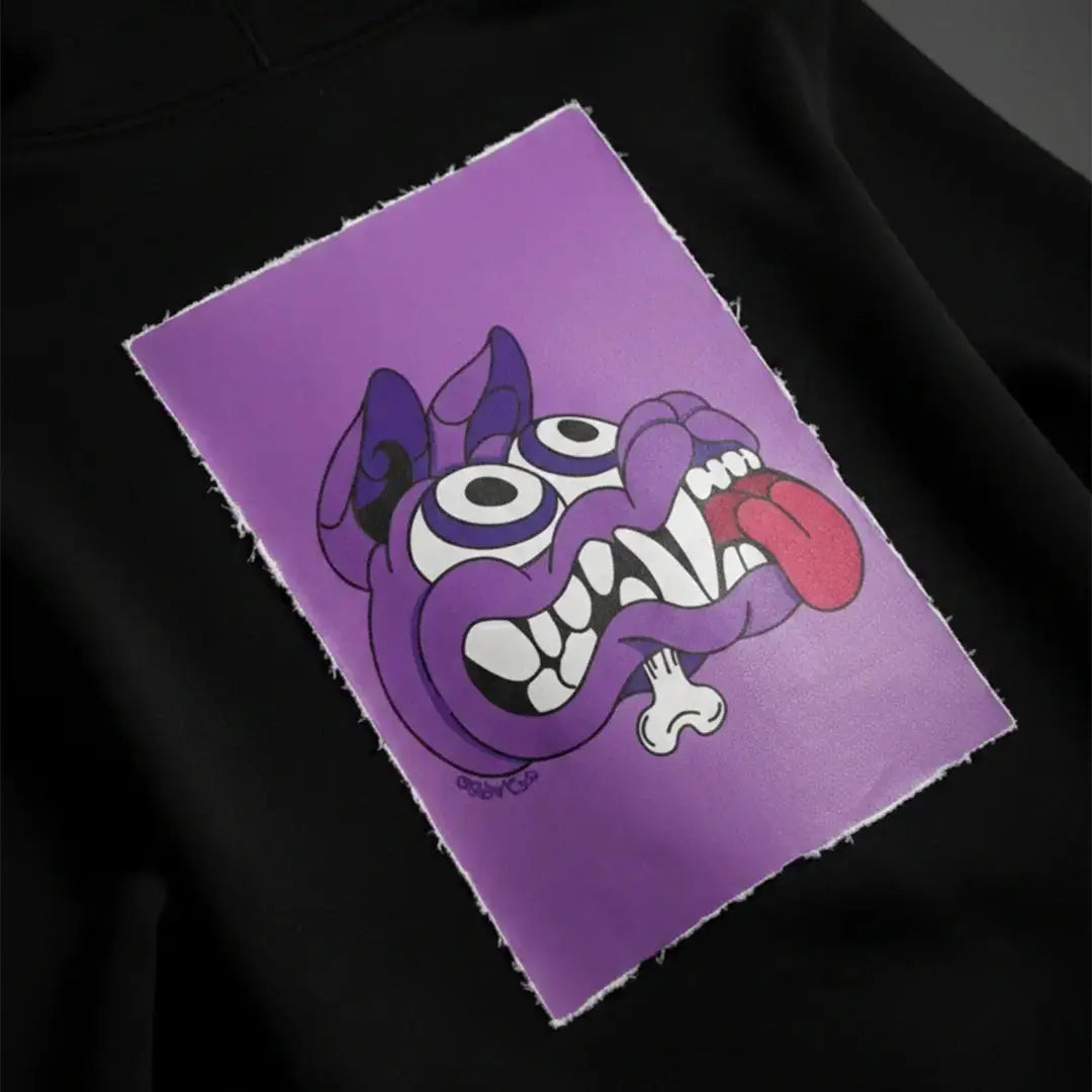 Toppa magnetica Cryptic Mad Dog viola su felpa nera, stile illustrato con dettagli eccentrici, ideale per personalizzare felpe Cryptic con stile unico.