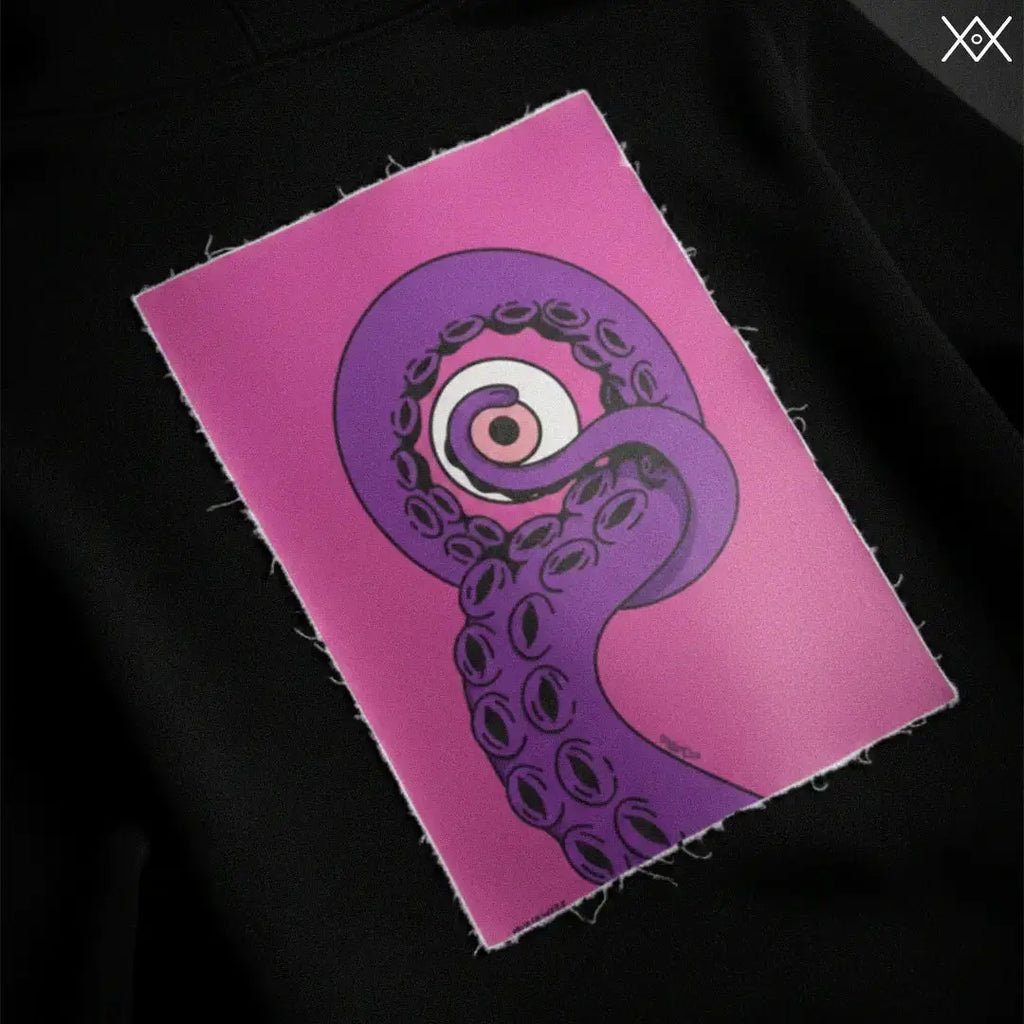 Cryptic EnKrak - Patch Magnetica per Felpa con illustrazione di tentacolo viola su sfondo rosa, applicato su felpa Cryptic nera.