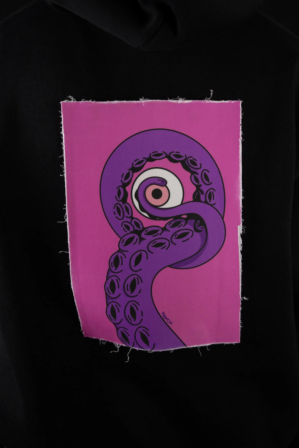 Patch intercambiabile Cryptic EnKrak con design artistico di tentacolo viola, bordo sfrangiato su felpa Cryptic nera, ideale per look personalizzati.